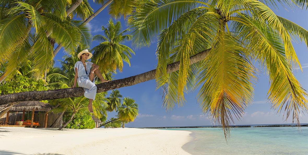 mujer sentada sobre palmera, Sun Aqua Vilu Reef