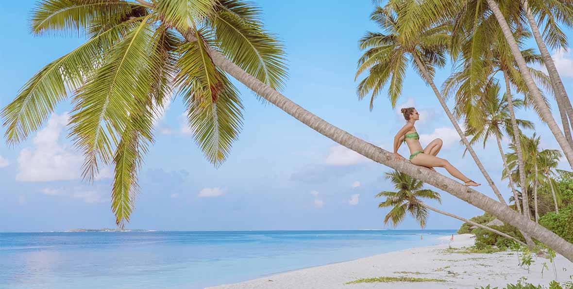 mujer sobre palmera en Reethi Faaru Resort